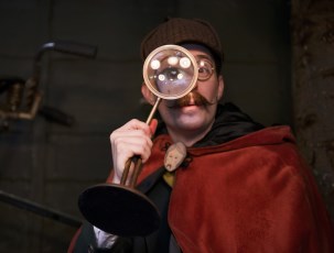 This image is of a professor holding a magnifying glass over his eye