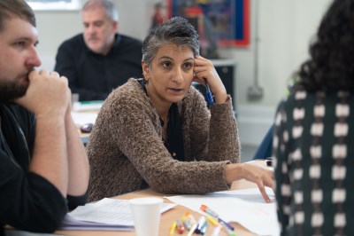 Four people sitting on chairs at a table 2 females and one male with large paper and coloured pens in front of them