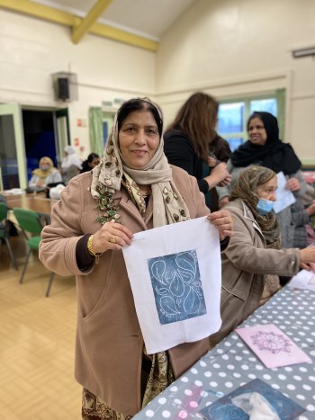 This image shows a lady holding up a piece of artwork she has created
